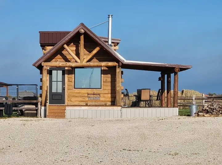 Solid-log cabin with a large covered porch and gable trim