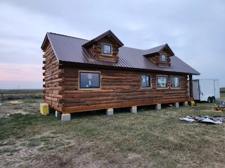 Large solid-log cabin with roof dormers, delivered